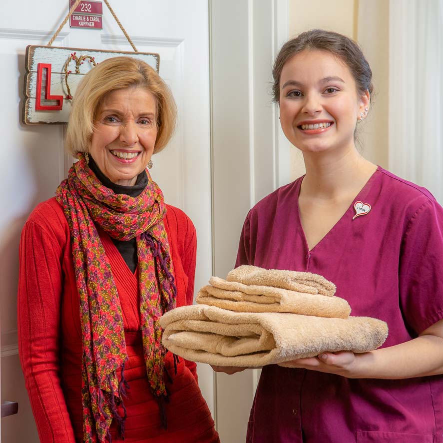 A team member delivering fresh linens to a resident at Jordan Oaks